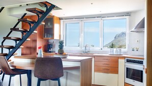 Une cuisine moderne dotée d’un îlot central, de meubles en bois, d’une cuisinière encastrée et d’une grande fenêtre offrant une vue sur l’extérieur.