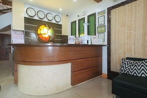A reception desk with a wooden finish, multiple clocks, framed certificates, and a decorative glass panel. - RedDoorz @ Nick Hotel Isabela (Alicia)