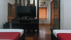 A room with a TV, two beds, a wooden cabinet, and a sliding door. - RedDoorz @ Nick Hotel Isabela (Alicia)