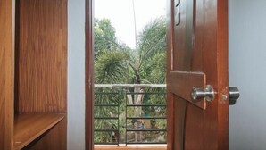 A wooden door with a metal gate, leading to a balcony with a view of greenery. - RedDoorz @ Nick Hotel Isabela (Alicia)