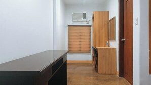 A narrow hallway with a dark wooden bench, a small wooden cabinet, and a door with a mirror. - RedDoorz @ Nick Hotel Isabela (Alicia)