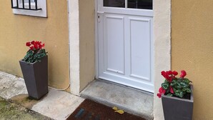 A white door with a glass panel, a small window with metal bars, and a security camera. - House Rustrel between Ochres and lavenders 3 bedrooms (Rustrel)