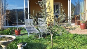 A yellow building with a garden area featuring outdoor seating, potted plants, and a birdbath. - House Rustrel between Ochres and lavenders 3 bedrooms (Rustrel)