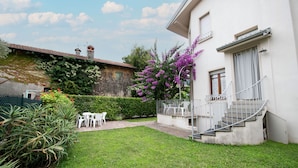 A courtyard with a white building, a staircase, and a garden with various plants. - Villa Ada in Toscolano-maderno (Toscolano Maderno)