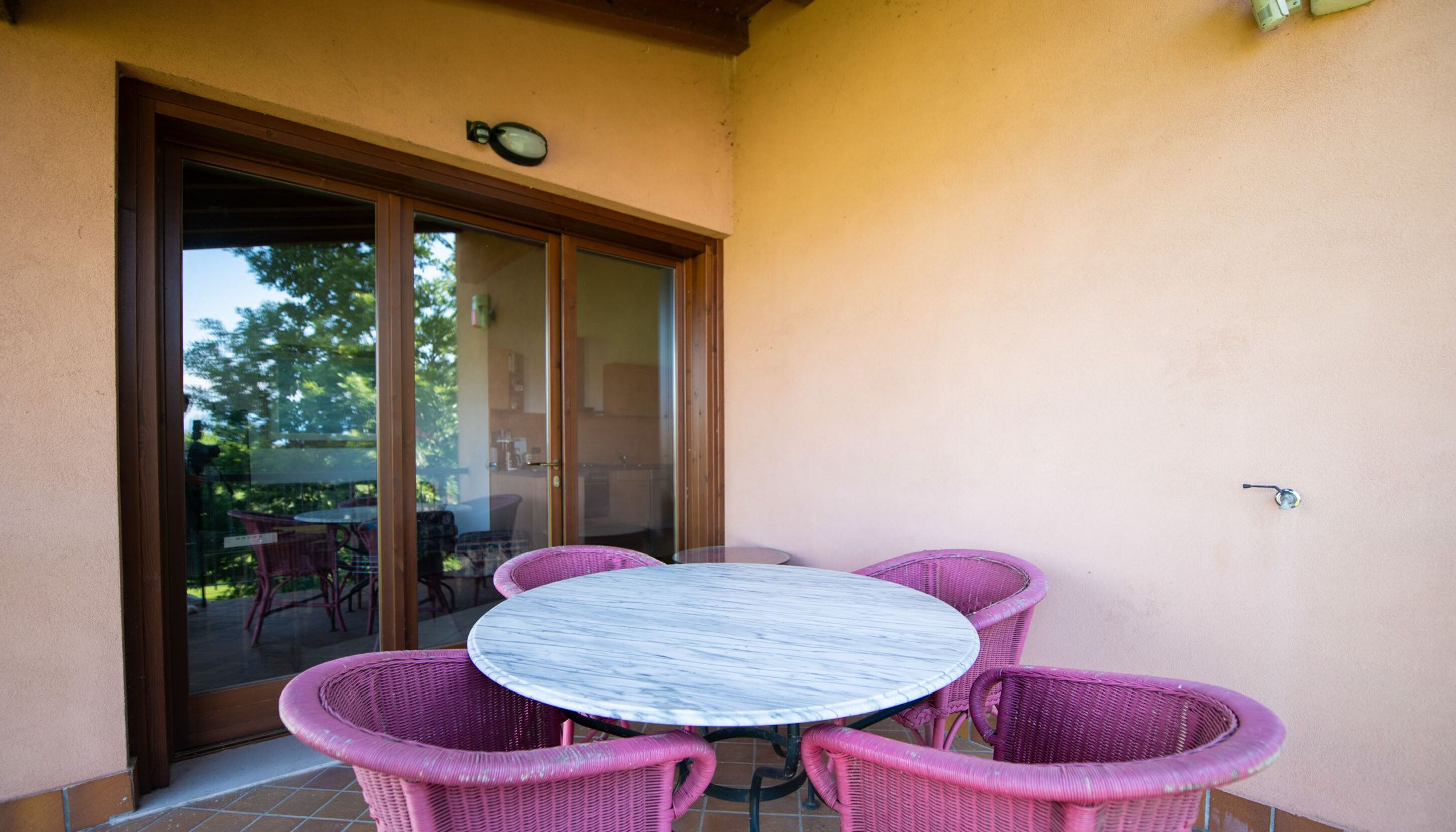 A patio with a round table and four wicker chairs.