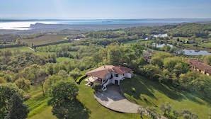 An aerial view of a large estate with a central house surrounded by lush greenery and a body of water in the background. - Villa Anna Miralago in Puegnago sul Garda (Puegnago del Garda)