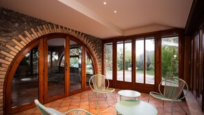 A spacious patio with a stone archway, a glass door leading outside, and a view of a green landscape.