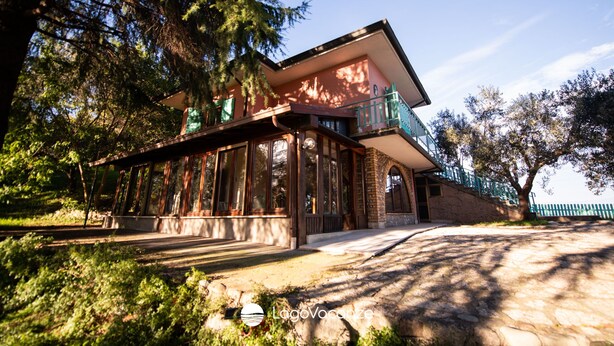 A two-story house with a balcony, surrounded by trees.