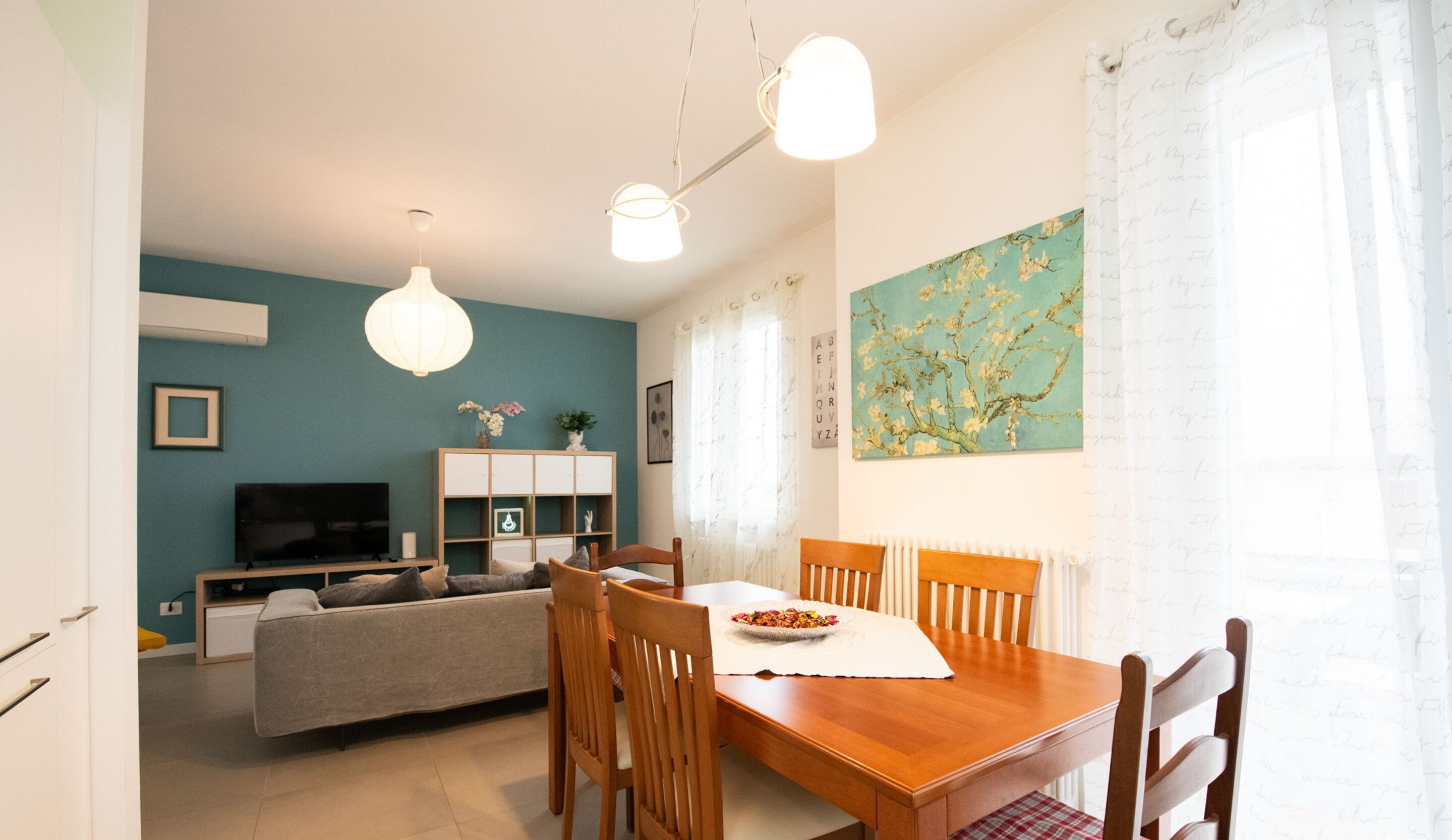 A modern living room with a sofa, TV, wooden dining table, and chairs.