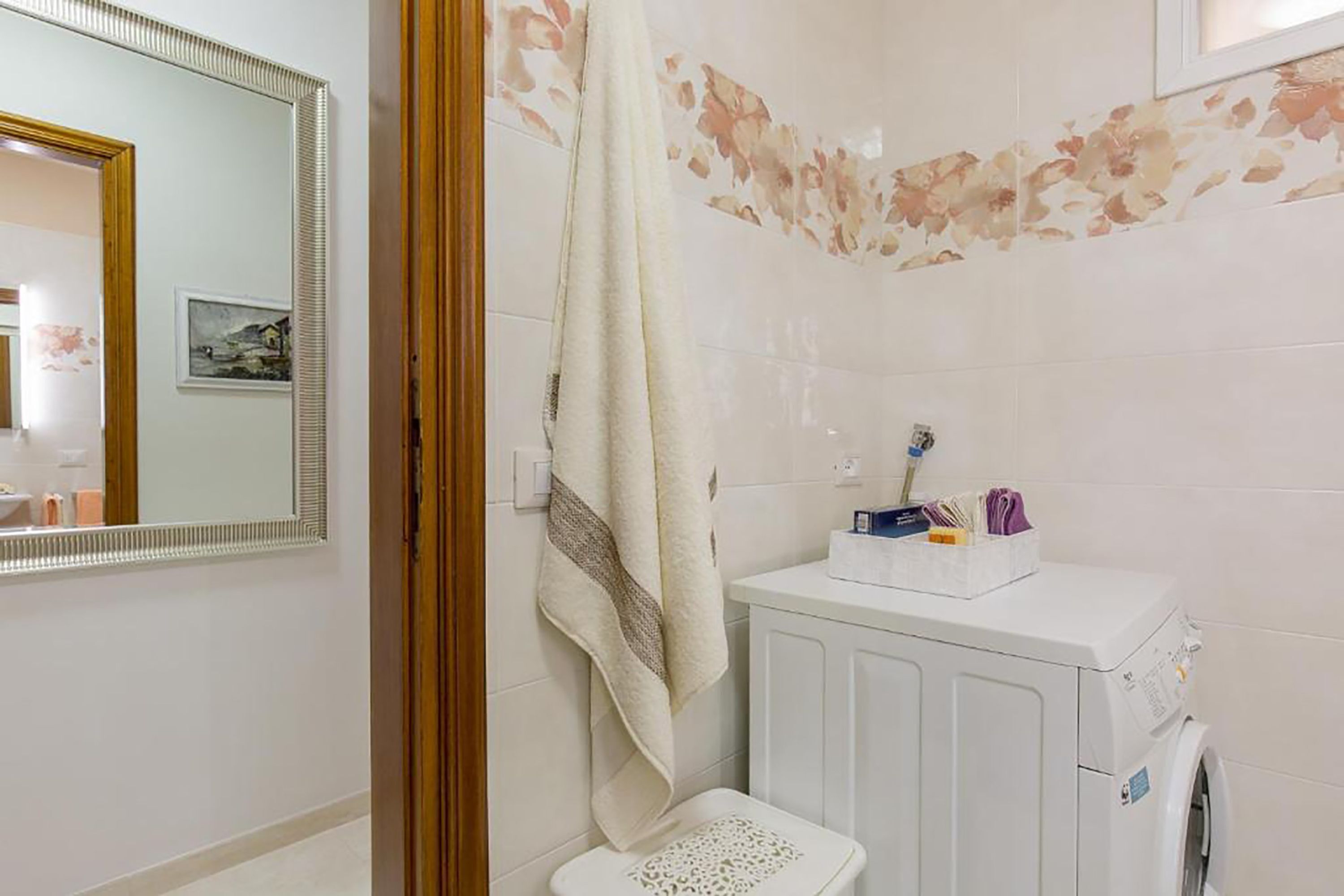 A bathroom with a white sink, a mirror, a towel hanging on the wall, and a washing machine.