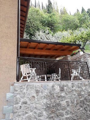 A stone wall with a wooden pergola and metal railing. - Giardino dei Limoni in Toscolano-maderno (Toscolano Maderno)