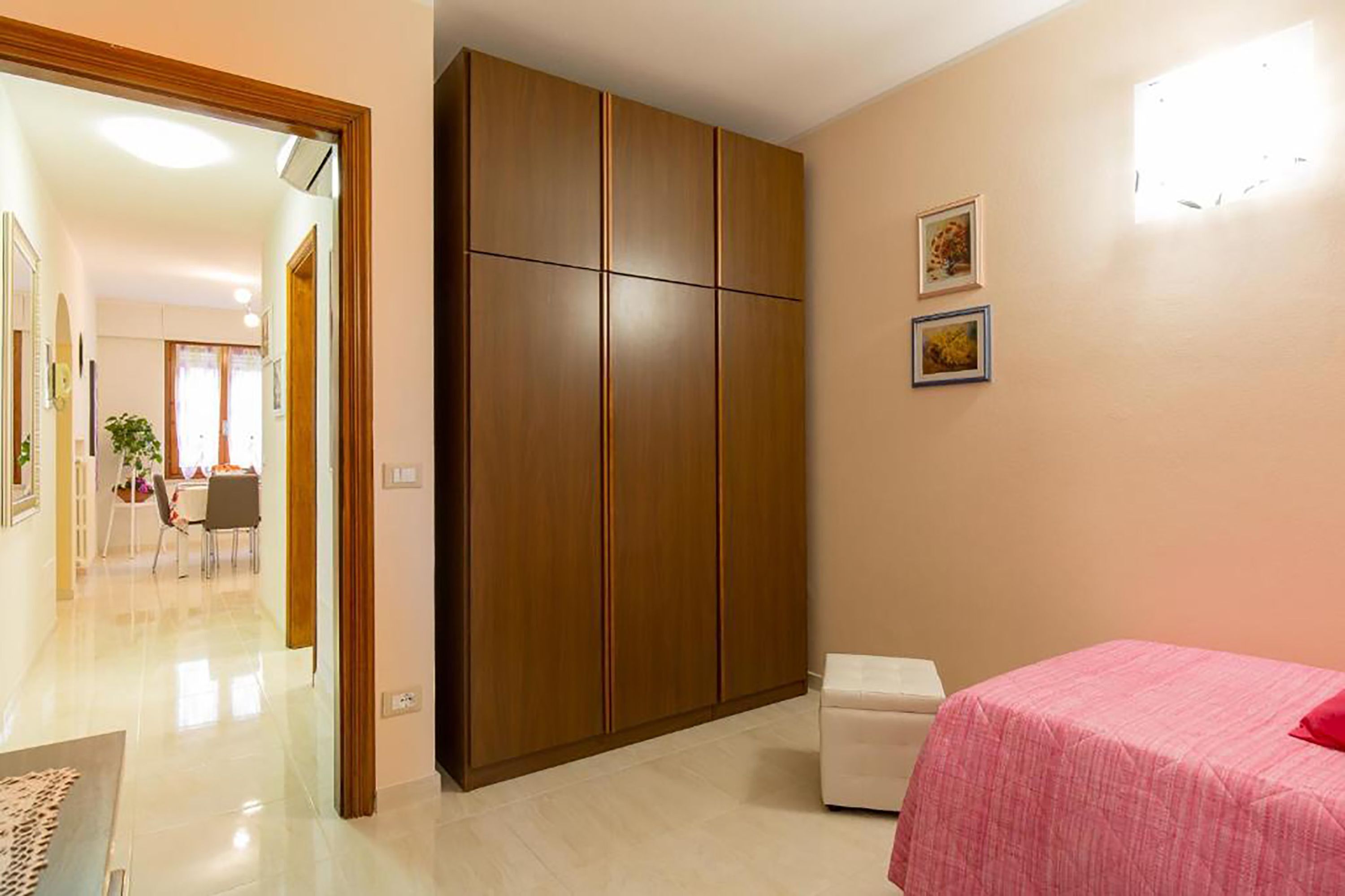 A bedroom with a bed, a wardrobe, and a small table.