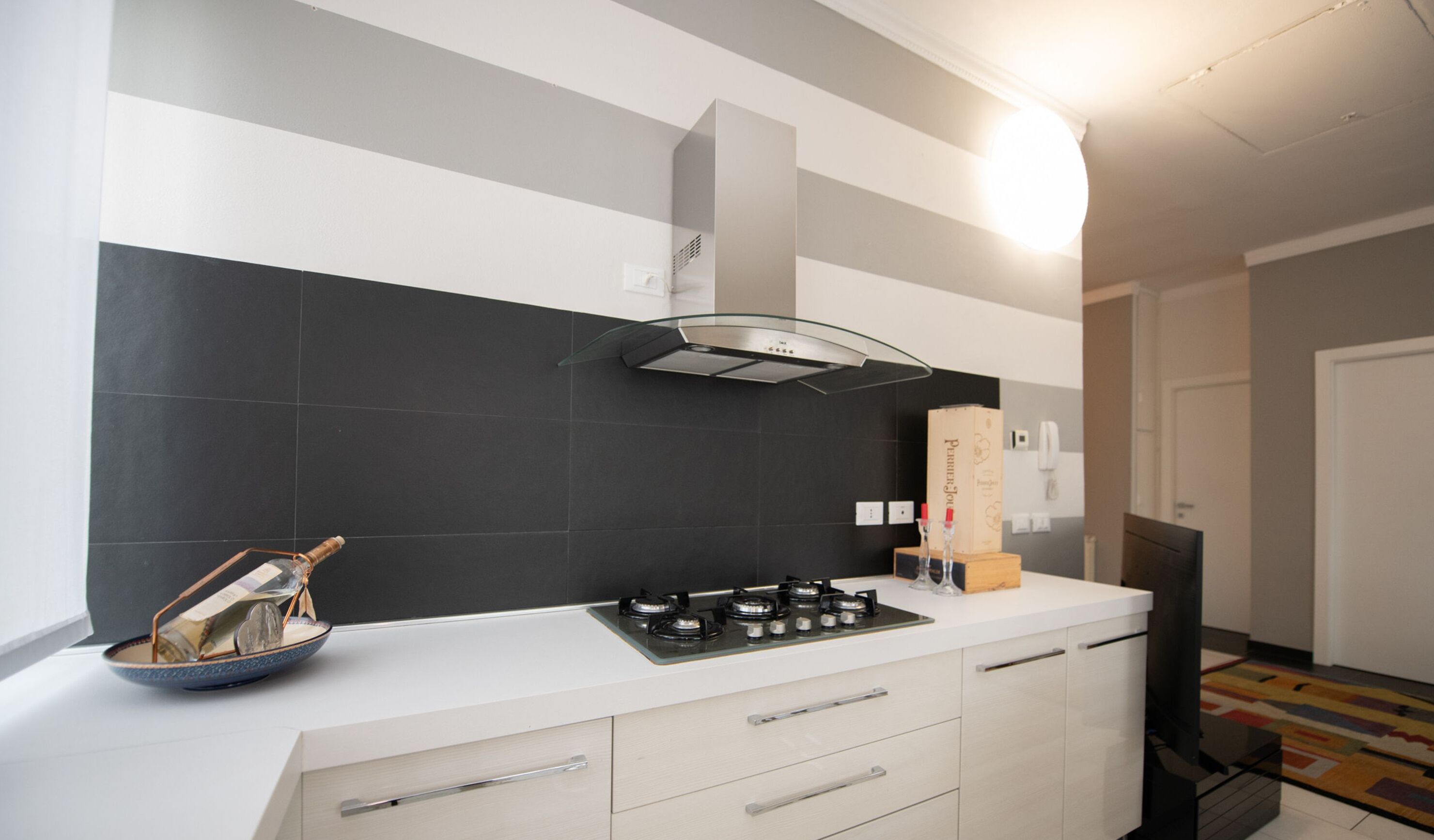 A modern kitchen with a gas stove, a stainless steel range hood, and a white countertop.