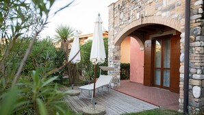 A stone building with an arched entrance, a wooden deck, and two white umbrellas. - Villaggio Tavaredo - App 02 (Polpenazze del Garda)