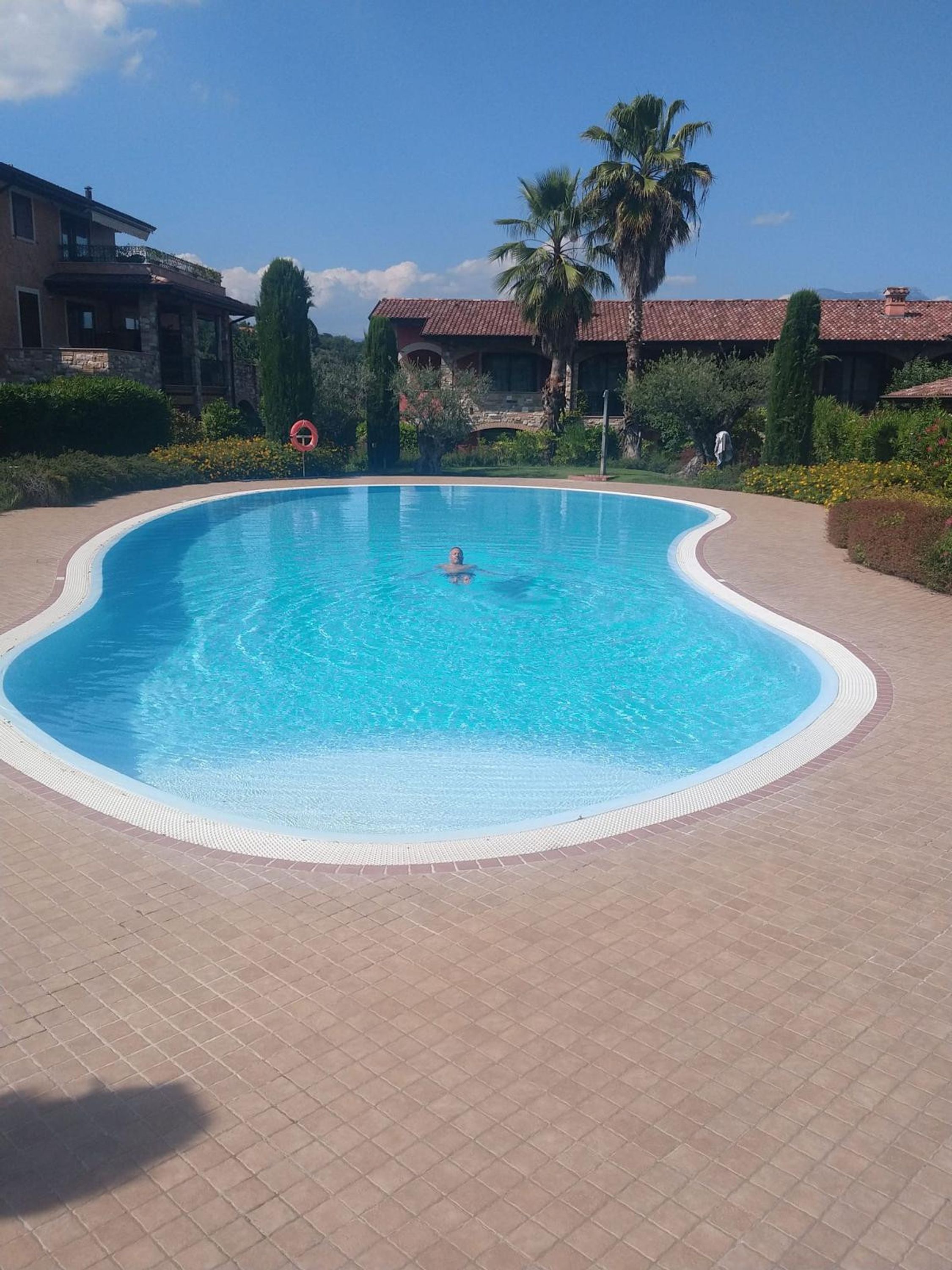A swimming pool with a curved edge, surrounded by a tiled deck.