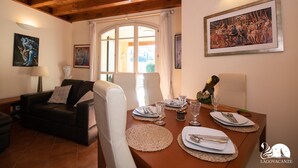A dining area with a wooden table set for four, surrounded by white chairs. - Borgo del Torchio - App H5 (Manerba del Garda)