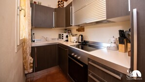 A modern kitchen with dark cabinets, a stainless steel sink, and a built-in oven. - Borgo del Torchio - App H5 (Manerba del Garda)