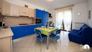 Eine moderne Küche mit blauen Schränken, einem Esstisch mit Stühlen und einem blauen Sofa im Wohnbereich.