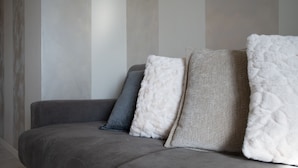 Un sofá gris con tres almohadas en tonos de gris y blanco.