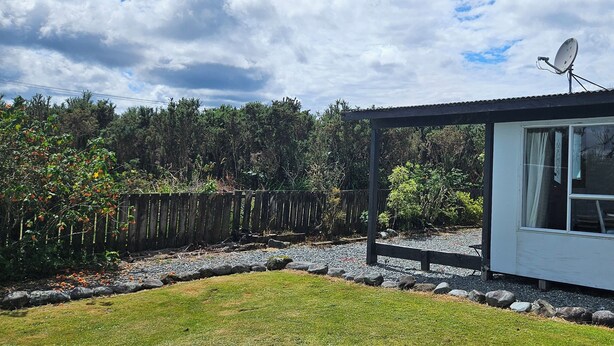 A small, single-story house with a covered porch, a satellite dish, and a gravel driveway. - Margs on The Corner
Home away from home
Nestled on the cycle trail (Kumara)
