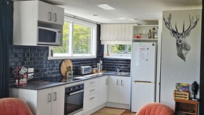 A compact kitchen with white cabinets, a microwave, a refrigerator, and a window providing natural light. - Margs on The Corner
Home away from home
Nestled on the cycle trail (Kumara)