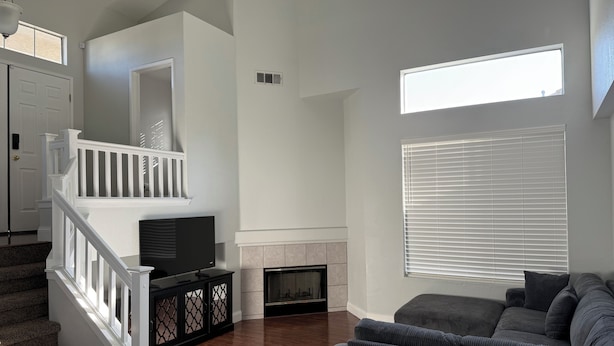A living room with a fireplace, a staircase, and a large window. - Spacious Waterfront Home for Groups (Stockton)