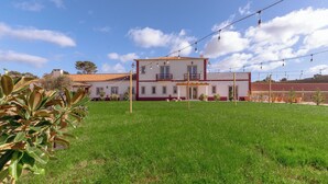 Una casa de dos pisos con fachada roja y blanca, un balcón y luces colgantes.