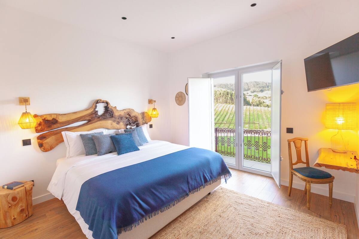 A bedroom with a large bed, wooden headboard, and a view of a garden through a sliding glass door.