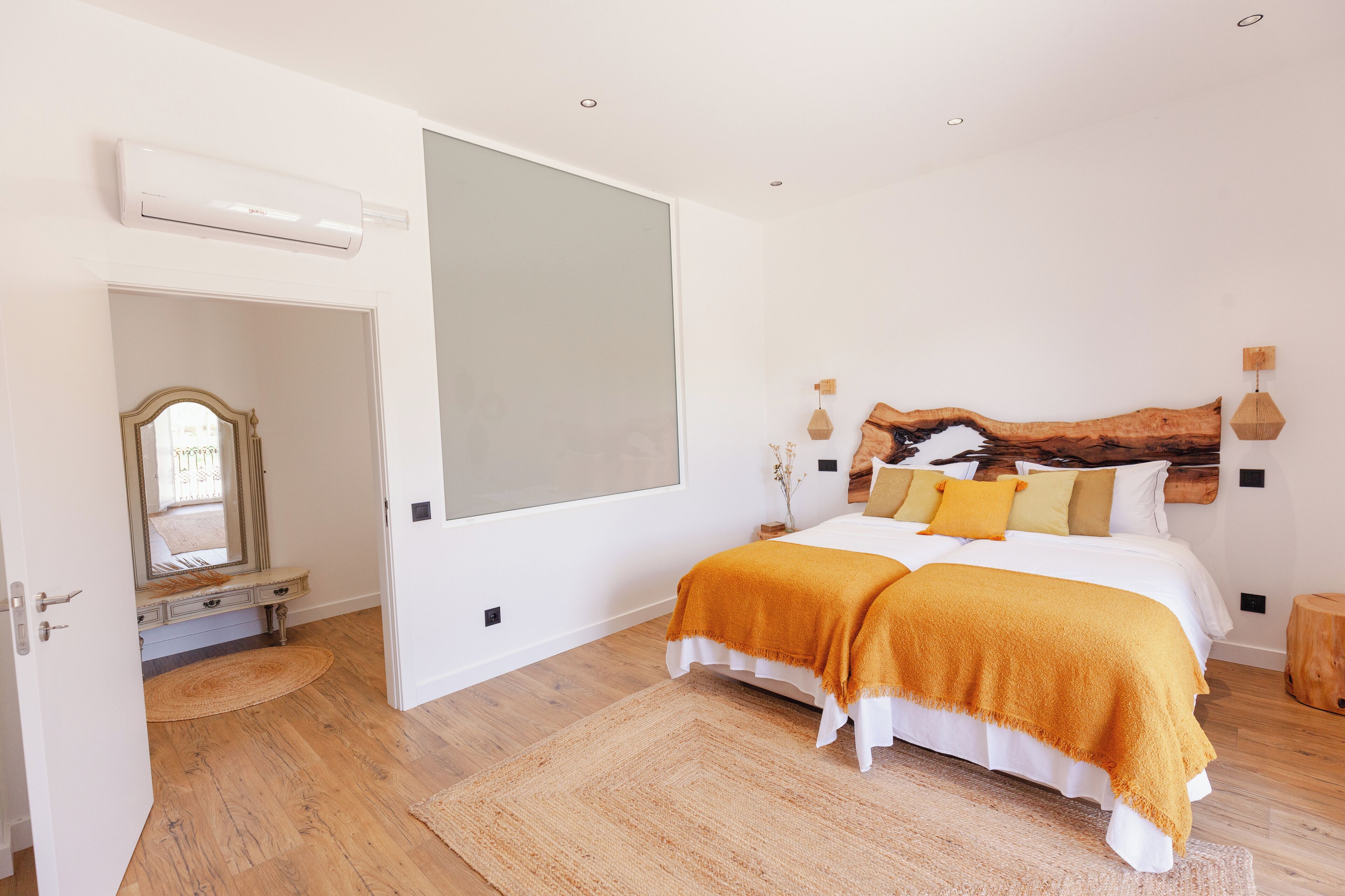 A bedroom with a large bed, a mirror, and a wooden headboard.