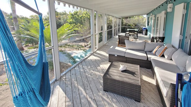 A covered outdoor seating area with a hammock, a sofa, and a table. - Colibri Oasis 3-BR Villa in wonderful Grace Bay with Pool steps from your door! (Grace Bay)