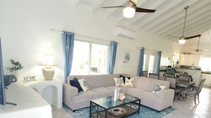 A spacious living area with a sofa, coffee table, and dining area. - Colibri Oasis 3-BR Villa in wonderful Grace Bay with Pool steps from your door! (Grace Bay)