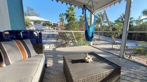 A covered outdoor seating area with a wicker sofa and a hammock. - Colibri Oasis 3-BR Villa in wonderful Grace Bay with Pool steps from your door! (Grace Bay)