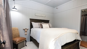 A bedroom with a bed, a chair, a bedside table, and a wall-mounted light fixture. - Cozy cabin on the Creek with WiFi and AC in delightful Belton (Belton)