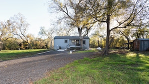 A two-story house with a front porch, surrounded by trees and a gravel driveway. - Cozy cabin on the Creek with WiFi and AC in delightful Belton (Belton)