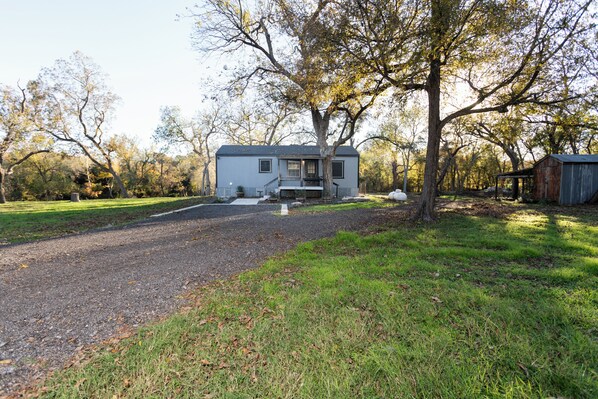 A two-story house with a front porch, surrounded by trees and a gravel driveway. - Cozy cabin on the Creek with WiFi and AC in delightful Belton (Belton)