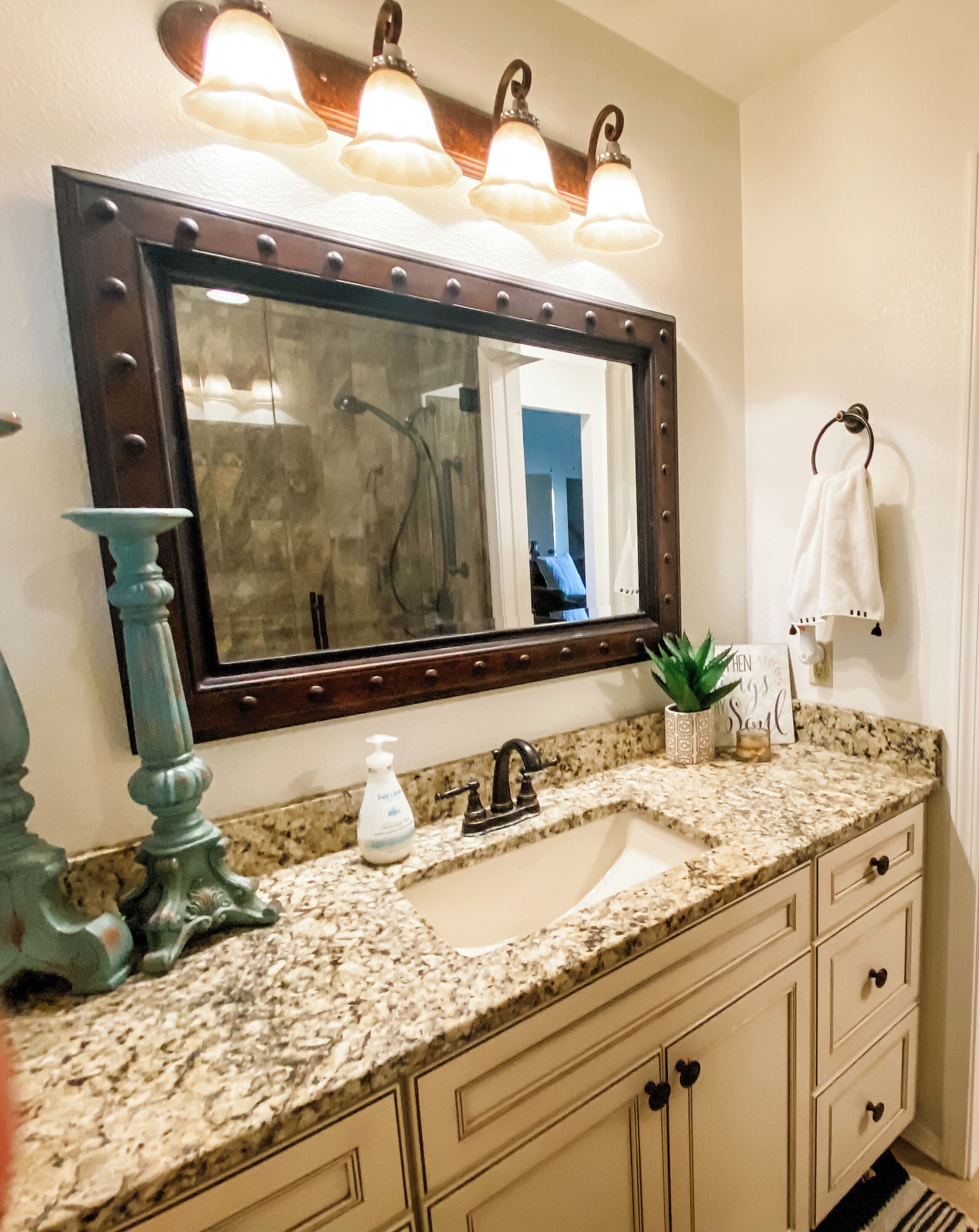 A bathroom with a large mirror, a sink, and a vanity with drawers.