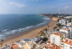 A coastal view with a beach, buildings, and a clear sky.