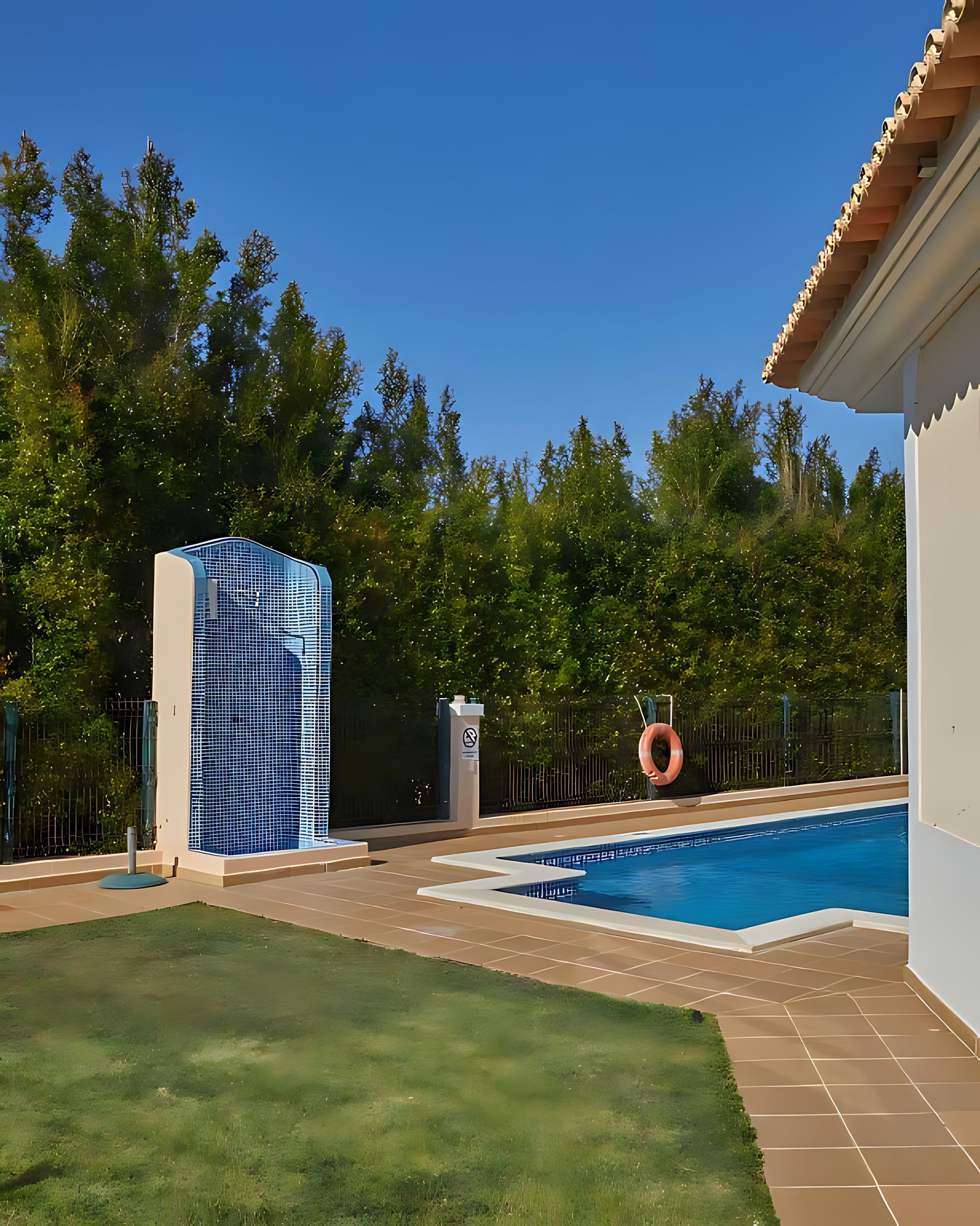 A swimming pool with a tiled deck, surrounded by a fenced area and a building with a blue and white facade.