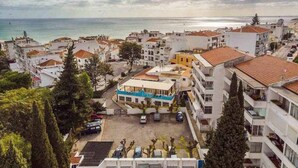 Eine Küstenstadt mit weißen Gebäuden, ein blaues Gebäude mit Balkon und Blick auf das Meer.