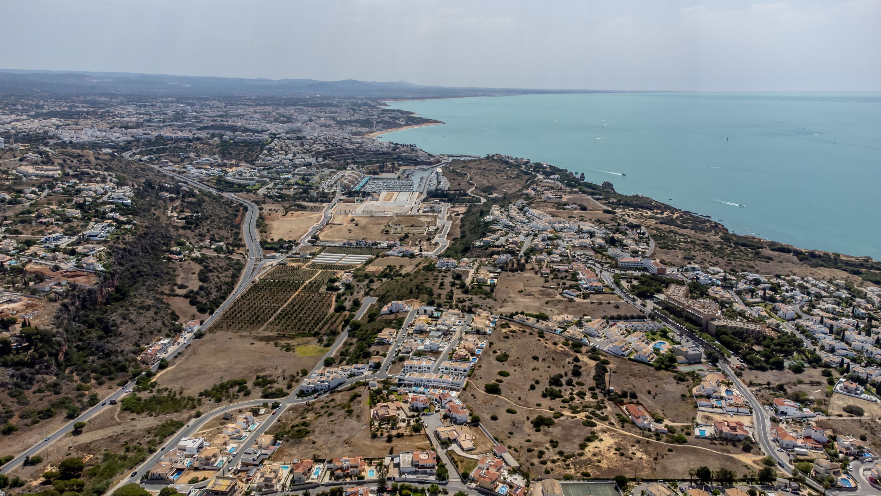 An aerial view of a coastal town with residential areas, a large industrial complex, and a beach.