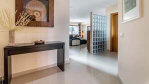 Un pasillo moderno con una consola, un espejo decorativo y un panel de vidrio con diseño de cuadrícula.