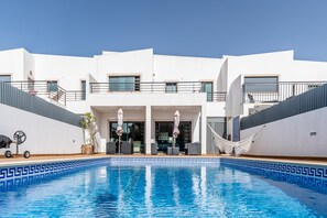 A modern building with a swimming pool, outdoor seating, and a white facade. - Villa Feliz Algarve V3 Sesmarias (Albufeira)