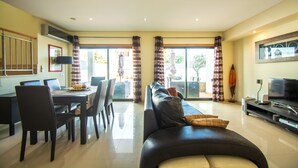 Un salón amplio con una mesa de comedor, sillas, un sofá y una televisión.
