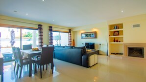 Un salón amplio con sofá, una mesa de comedor con sillas, una chimenea y un televisor.