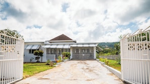 A gated entrance to a house with a sloped roof and a small porch. - RVR Rentals (Montego Bay)