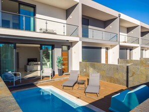 A modern multi-story building with a swimming pool, outdoor seating, and a balcony. - Villa Alegre With Private Pool (Albufeira)