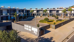A modern multi-story hotel with a courtyard, solar panels on the roof, and palm trees.