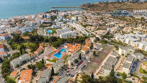 Vue aérienne d’une ville côtière avec des immeubles résidentiels, une piscine et un port de plaisance.
