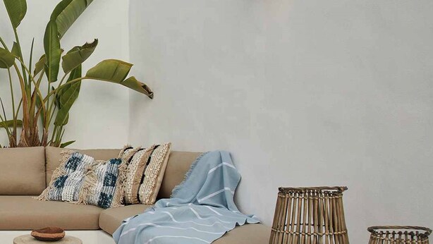 A modern living room with a beige sofa, a small round table, and two bamboo lamps.