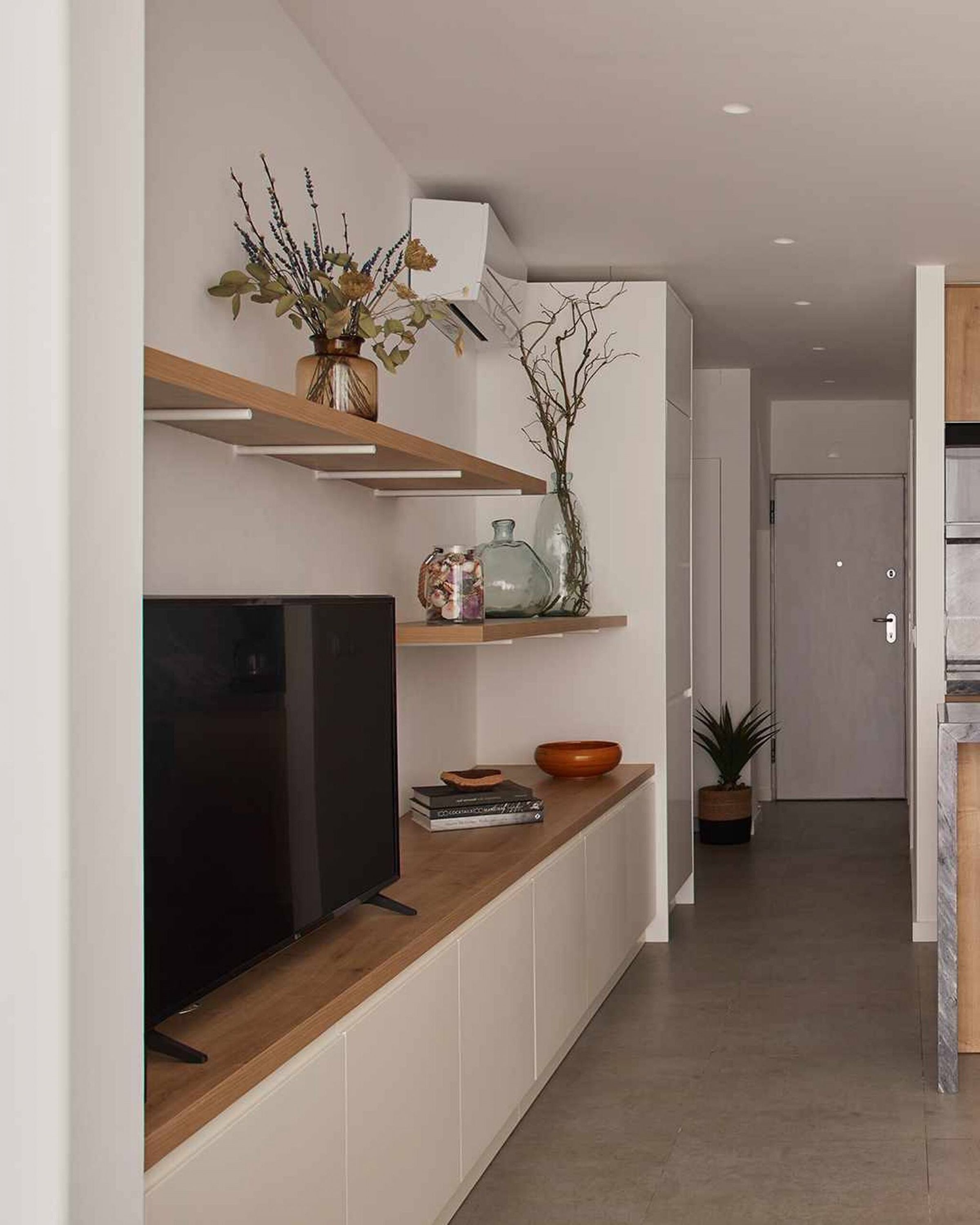 Una cocina moderna con televisor integrado, estantes de madera y elementos decorativos.